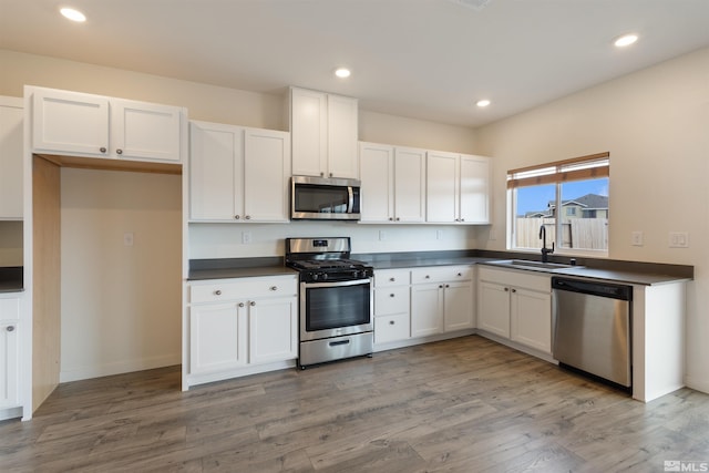 kitchen featuring dark countertops, white cabinets, stainless steel appliances, and a sink