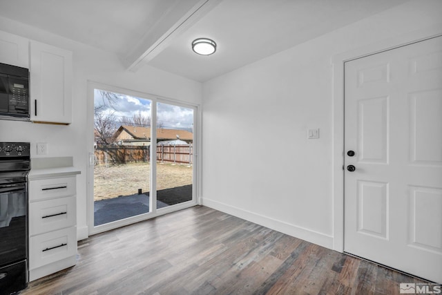 unfurnished dining area with beamed ceiling, wood finished floors, and baseboards