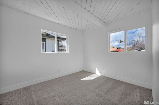 carpeted spare room with beam ceiling, baseboards, and wooden ceiling