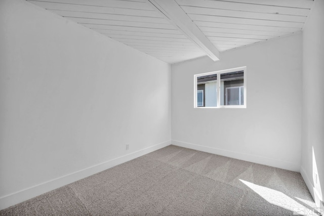 empty room with beamed ceiling, carpet flooring, and baseboards