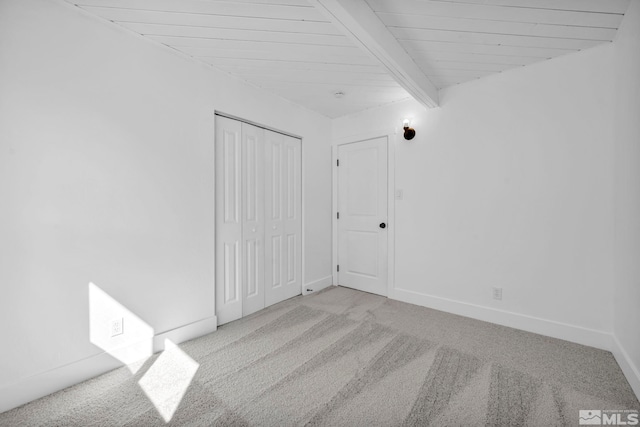 carpeted empty room with beamed ceiling, wood ceiling, and baseboards