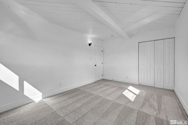 interior space featuring beamed ceiling, carpet floors, and baseboards