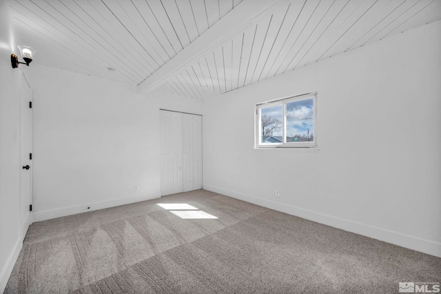 carpeted spare room featuring beamed ceiling, wooden ceiling, and baseboards