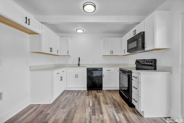 kitchen featuring black appliances, a sink, wood finished floors, white cabinets, and light countertops