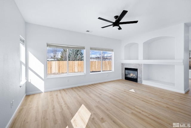 unfurnished living room featuring visible vents, a tiled fireplace, built in features, wood finished floors, and baseboards