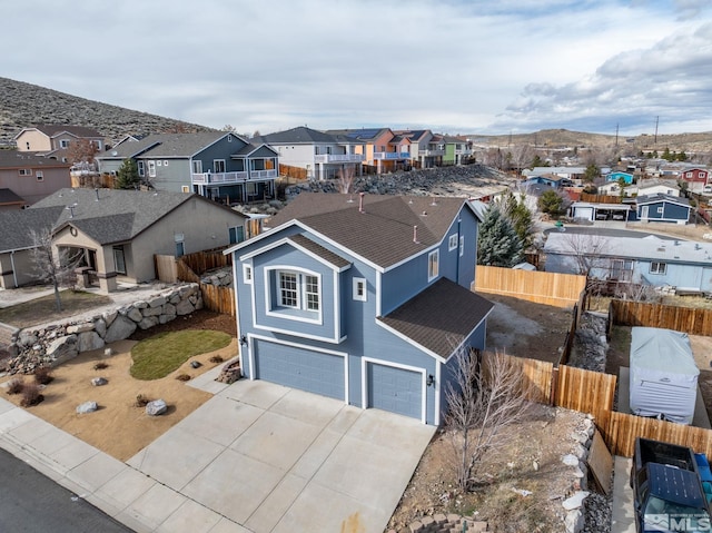 view of front facade with driveway, fence, a residential view, roof with shingles, and a garage