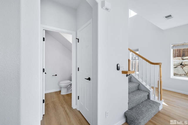 stairs featuring visible vents, baseboards, and wood finished floors