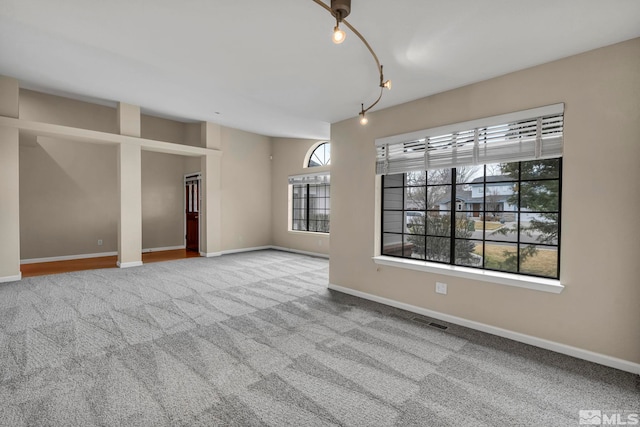 unfurnished room with visible vents, carpet floors, baseboards, and track lighting