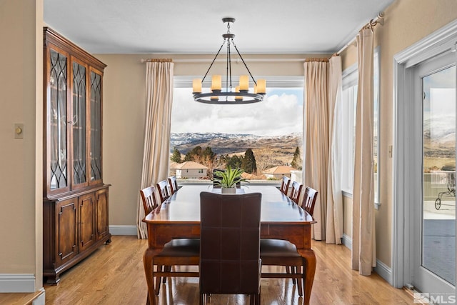 dining area featuring a notable chandelier, baseboards, and light wood finished floors