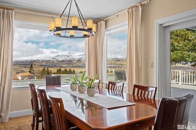 dining space featuring a notable chandelier, a mountain view, baseboards, and wood finished floors