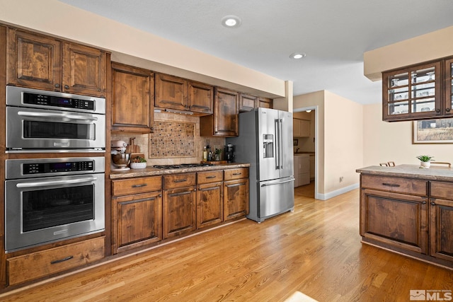 kitchen featuring baseboards, recessed lighting, stainless steel appliances, light wood-style floors, and backsplash