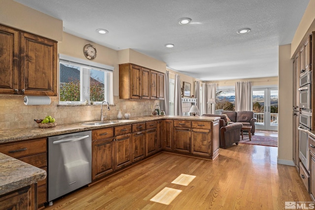 kitchen featuring a sink, light wood-style floors, appliances with stainless steel finishes, and open floor plan