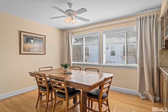 dining area with light wood-style flooring, baseboards, and ceiling fan