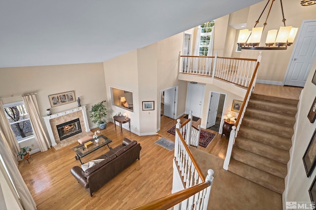 living room with baseboards, high vaulted ceiling, wood finished floors, and a fireplace