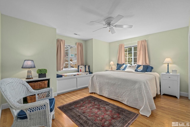 bedroom with light wood finished floors, visible vents, baseboards, and a ceiling fan