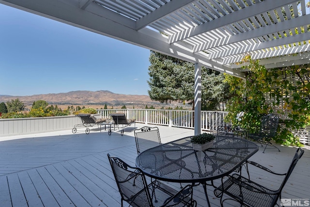 wooden deck with outdoor dining space and a mountain view