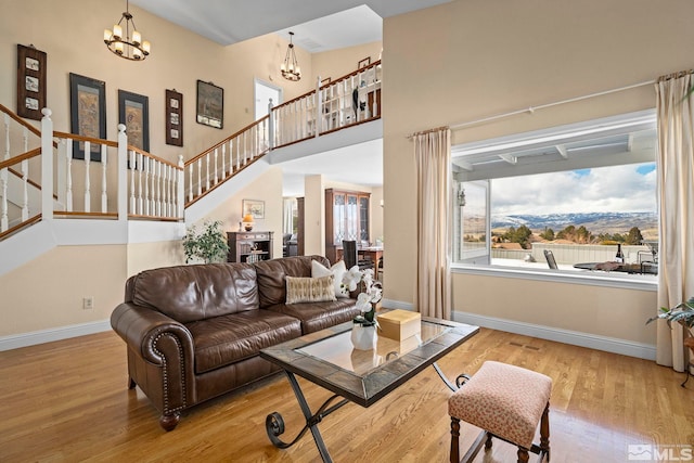 living area featuring wood finished floors, a high ceiling, baseboards, a chandelier, and stairs