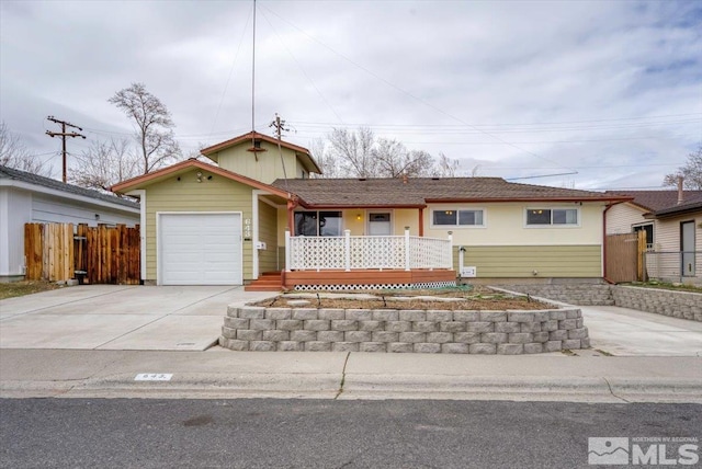 ranch-style house with an attached garage, covered porch, driveway, and fence