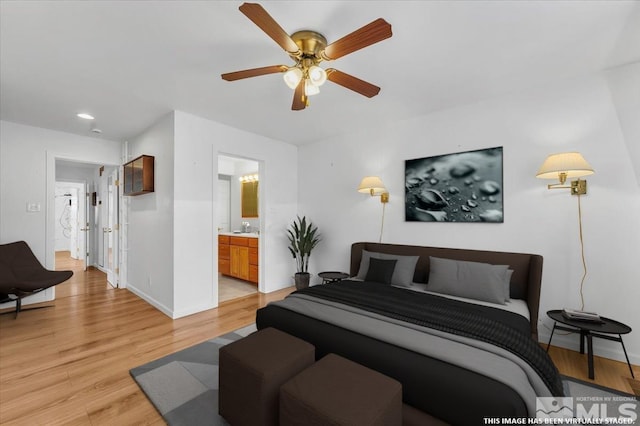 bedroom featuring baseboards, light wood finished floors, ceiling fan, a sink, and ensuite bathroom