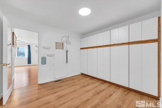 empty room with baseboards, visible vents, and light wood-type flooring