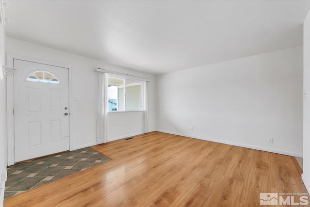 foyer featuring visible vents, baseboards, and wood finished floors