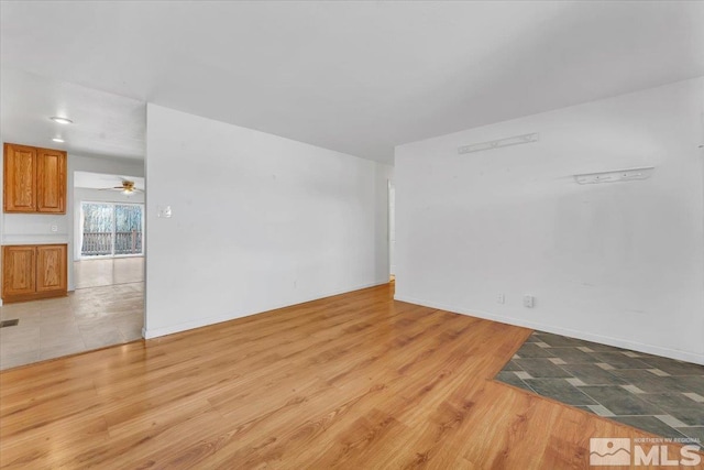 spare room with ceiling fan, baseboards, and light wood-style flooring