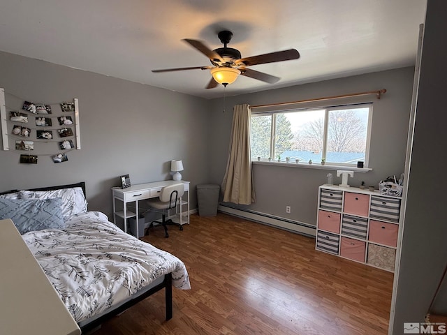 bedroom featuring ceiling fan, a baseboard heating unit, and wood finished floors