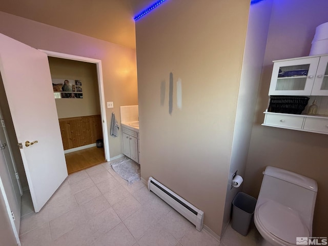 bathroom with a baseboard radiator, toilet, vanity, and tile patterned flooring