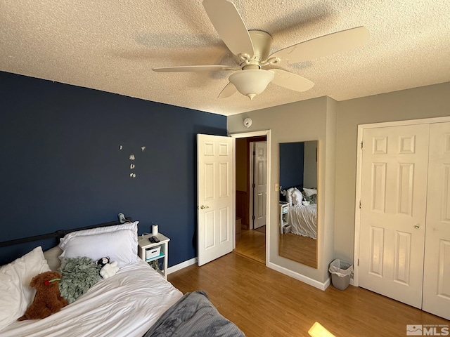 bedroom featuring baseboards, a textured ceiling, wood finished floors, and a ceiling fan