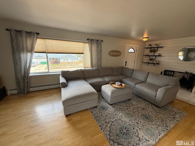 living room featuring light wood-type flooring, wood walls, and a baseboard radiator