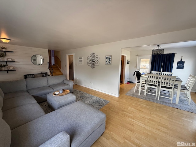 living area with wooden walls, light wood-style flooring, and baseboards