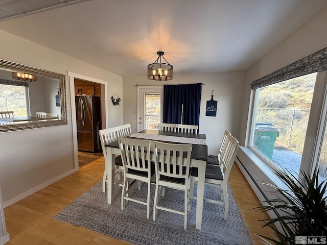 dining area featuring a notable chandelier, baseboards, and light wood-type flooring