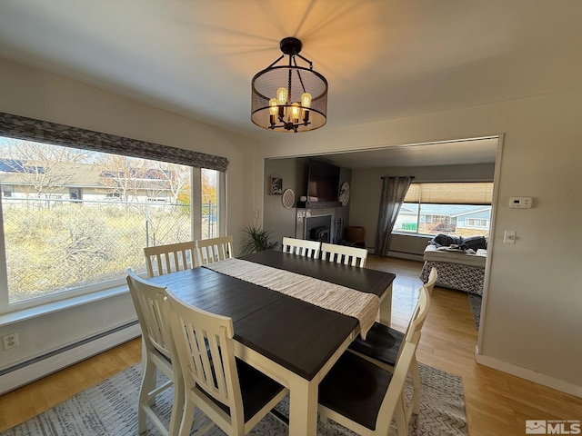 dining space featuring an inviting chandelier, wood finished floors, baseboards, and baseboard heating