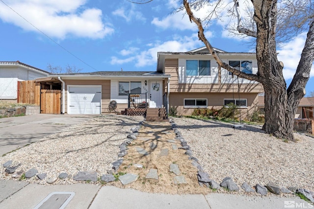 split level home with concrete driveway, fence, and a garage