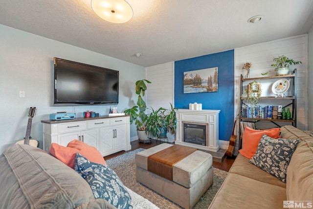 living room featuring a glass covered fireplace, a textured ceiling, and wood finished floors