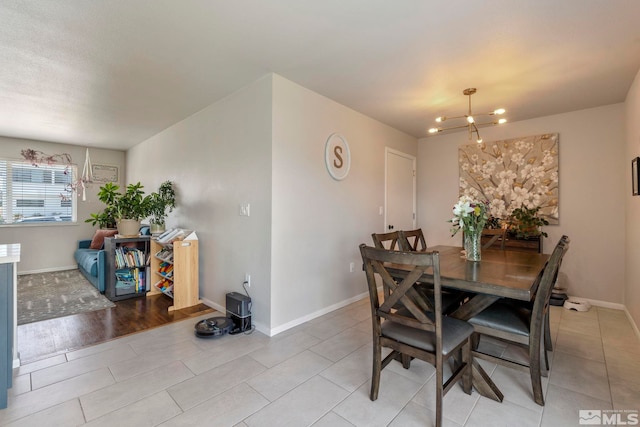 dining space with baseboards, an inviting chandelier, and light tile patterned flooring