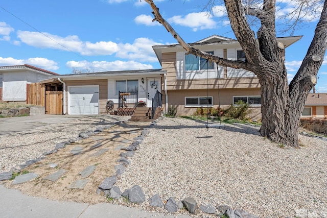 tri-level home with driveway, a garage, and fence