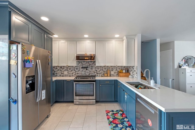 kitchen featuring light countertops, range hood, a peninsula, stainless steel appliances, and a sink