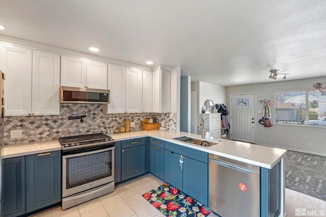 kitchen with appliances with stainless steel finishes, white cabinetry, a peninsula, and a sink