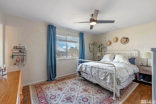 bedroom featuring baseboards, wood finished floors, and a ceiling fan