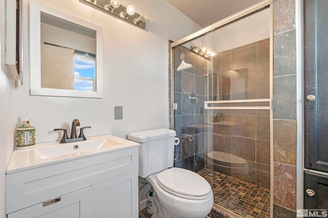 bathroom with a stall shower, toilet, and vanity