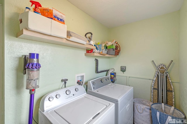 washroom featuring washing machine and clothes dryer, laundry area, and a wainscoted wall