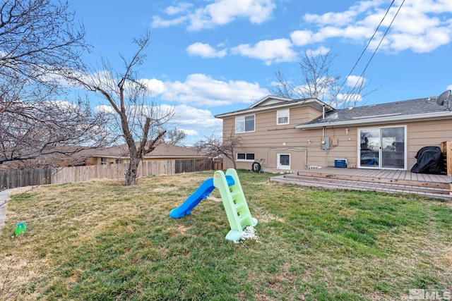 back of property with a yard, a wooden deck, and fence