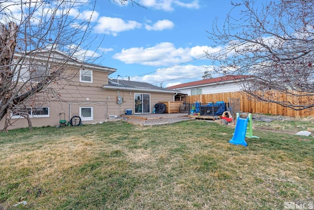 rear view of house featuring a yard, a deck, and fence