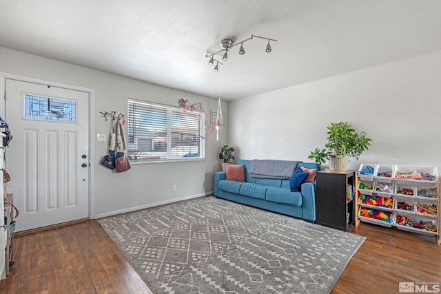 living room featuring baseboards, a textured ceiling, and wood finished floors