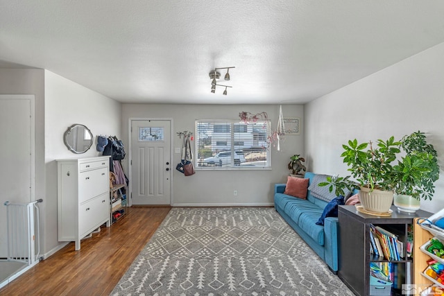 living area featuring wood finished floors, baseboards, and a textured ceiling