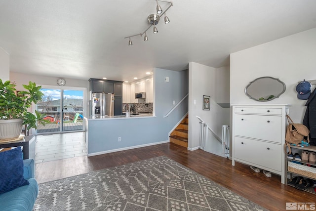 living area featuring baseboards, dark wood finished floors, and stairs