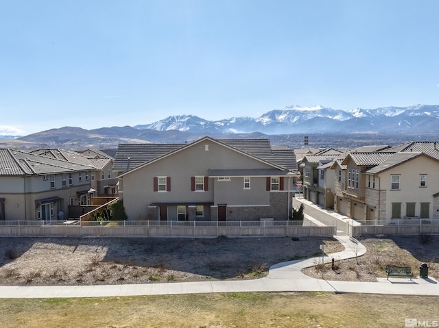 rear view of property with fence, a residential view, a tiled roof, stucco siding, and a mountain view