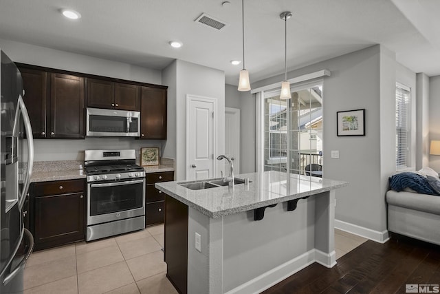 kitchen with visible vents, baseboards, dark brown cabinetry, stainless steel appliances, and a sink