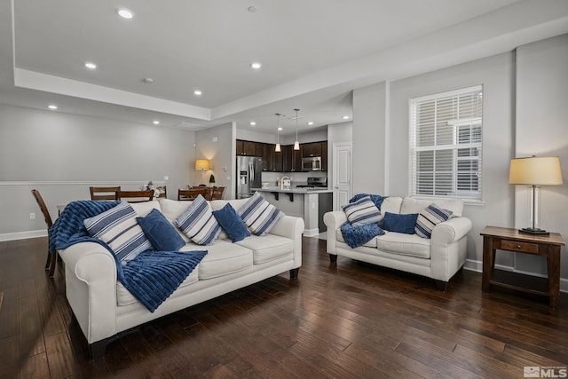 living area with hardwood / wood-style flooring, recessed lighting, baseboards, and a tray ceiling